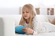 © Pixel-Shot - Cute little girl reading book on sofa at home