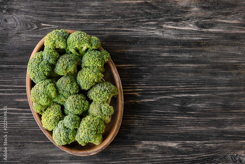 Bowl with fresh green broccoli on wooden table