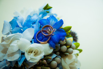 Wedding ring. Two gold romantic rings of the bride and groom are on a bouquet of blue and blue flowers