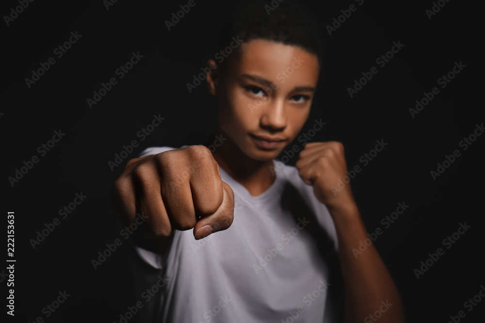 Bully African-American teenage boy on dark background