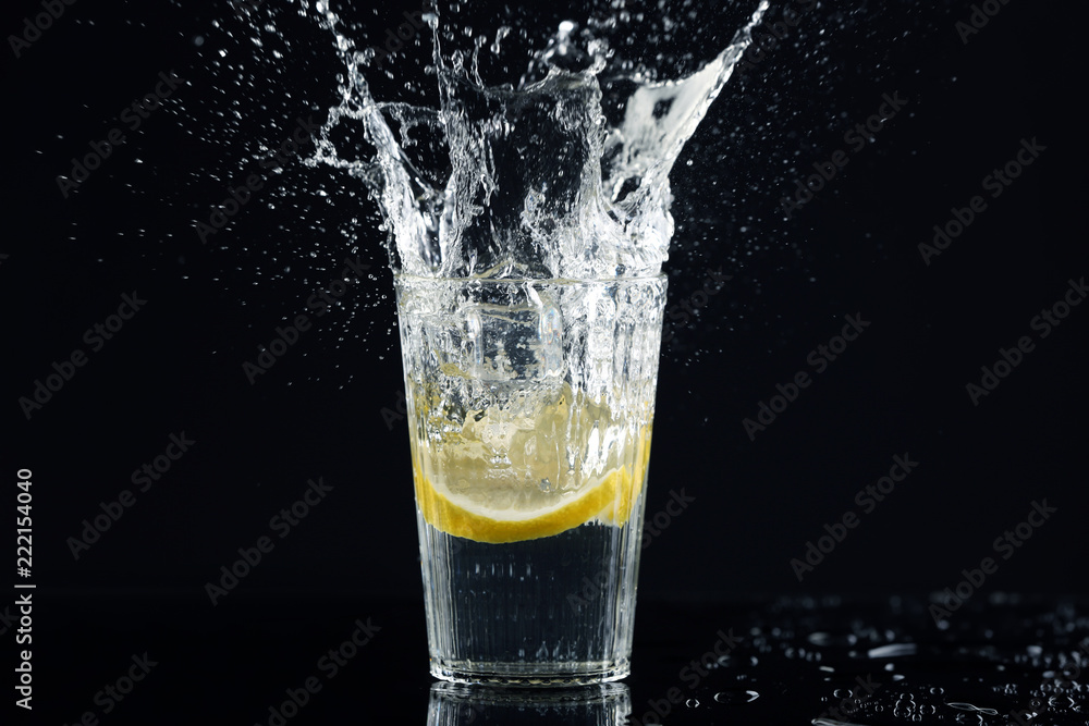 Glass of fresh lemonade with splashes on dark background