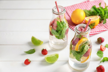 Bottles of fresh strawberry lemonade on light wooden table