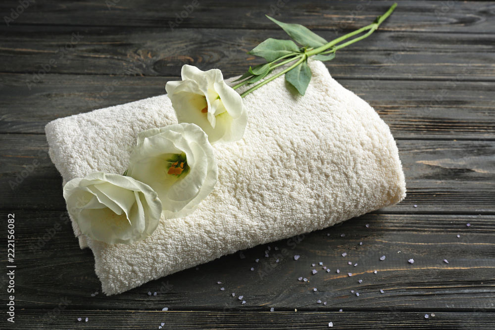 Soft towel with flowers on wooden table