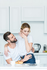 Wall Mural - happy young couple in love hugging while having breakfast together