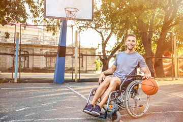 Wall Mural - Young man in wheelchair playing basketball outdoors