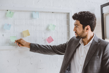 Wall Mural - handsome businessman taking sticker from task board in office