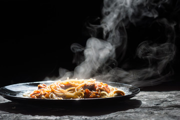 The steam from spaghetti with tomato sauce - homemade healthy italian pasta on dark background