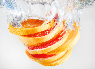 Wall Mural - Grapefruit and orange falling to the water. Suitable for advertisement.