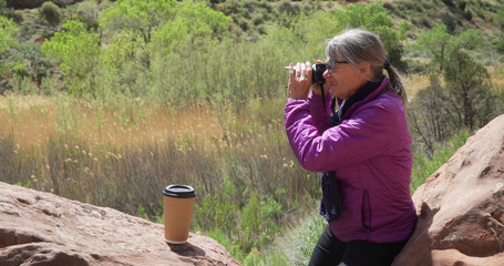 Wall Mural - Mature nature loving woman using camera to take pictures of wildlife Zion Utah