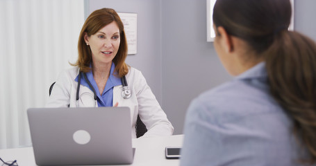 Wall Mural - Professional caucasian doctor discussing with young female patient about issues surrounding future surgery. Young patient consulting with medical doctor over her health condition