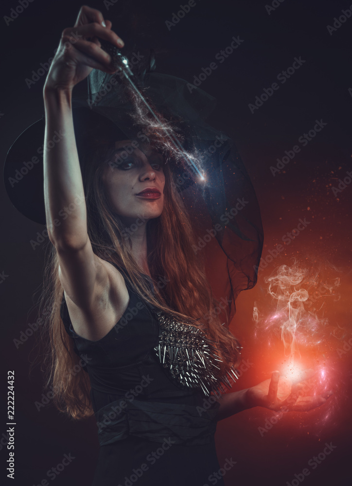 Young witch with a wand casting a spell in her ritual, halloween ...