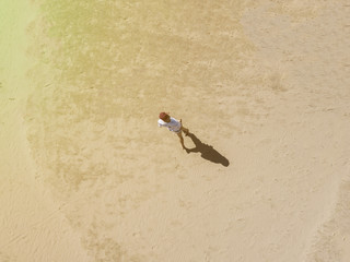 Wall Mural - aerial overhead view of young man walking alone in the sandy sea beach, abstract concept background f