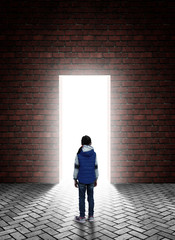 little girl is standing in front of a doorway in a brick wall behind which a bright white light
