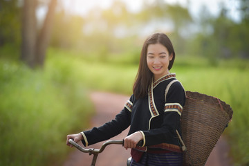 Wall Mural - Traditional Hmong girl with basket of agricultural crops walking with bicycles in forest Happy Hmong girl smiling with green nature in Sapa city, northern Vietnam