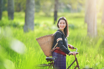 Wall Mural - Traditional Hmong girl with basket of agricultural crops walking with bicycles in forest Happy Hmong girl smiling with green nature in Sapa city, northern Vietnam