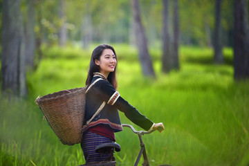 Traditional Hmong girl with basket of agricultural crops walking with bicycles in forest Happy Hmong girl smiling with green nature in Sapa city, northern Vietnam