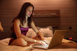 © Aleksei Lazukov - brunette work with a laptop at home on the bed in the evening