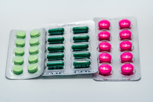Pink tablets and green capsule and green tablets in blister pack on white background. Painkiller medicine. Pharmaceutical industry. Pharmacy drugstore background. Pharmacy products. Global healthcare.