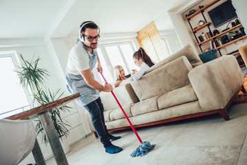 Husband housekeeping and cleaning concept. A man cleans the house, while women gossiping on the sofa