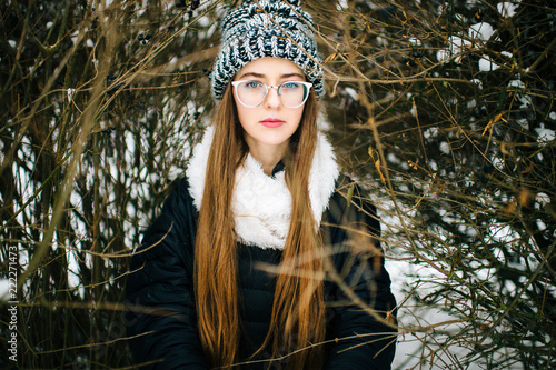 Fotografie, Obraz Mood dramatic winter lifestyle outdoor portrait of young amazing girl in wool stylish hat and glasses looking deep at camera