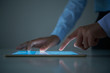 © DragonImages - Crop hands of unrecognizable businessman enlarging and scrolling data on modern tablet on table in dark office