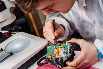 Close up hands of a service worker repairing digital camera.