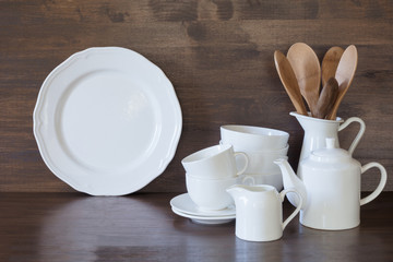 Crockery, clayware, white utensils and other different stuff on wooden tabletop. Kitchen still life as background for design. Copy space.