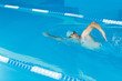 © Sergey - Photo of young sports man in blue cap swimming in pool