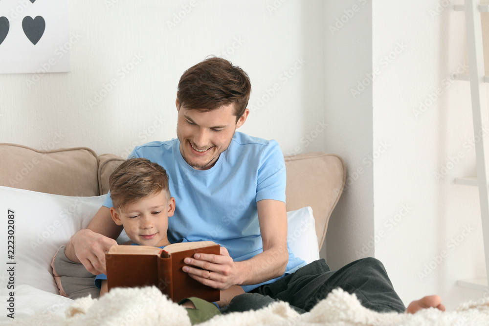 Father and his son reading book together at home