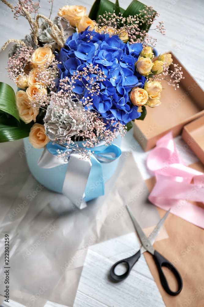 Gift box with beautiful flowers on table of florist