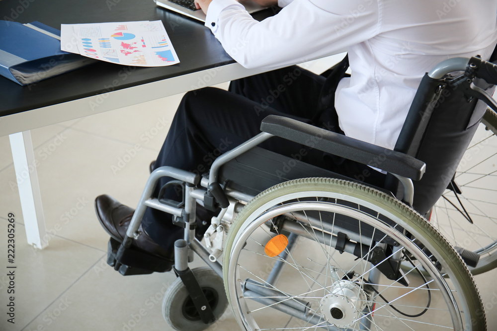 Businessman in wheelchair working with laptop in office