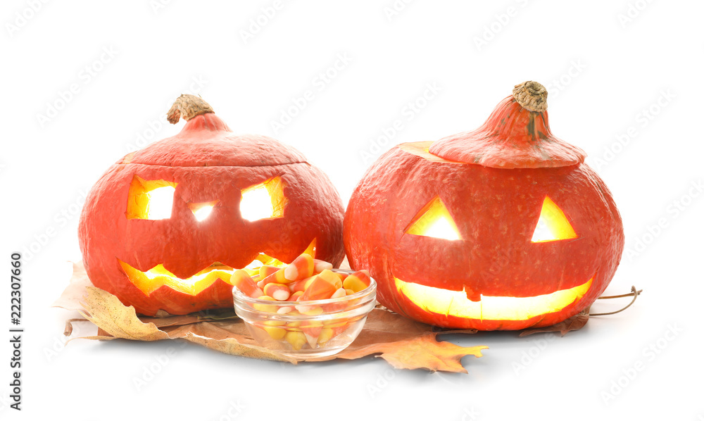 Halloween pumpkins with candies and dry leaves on white background