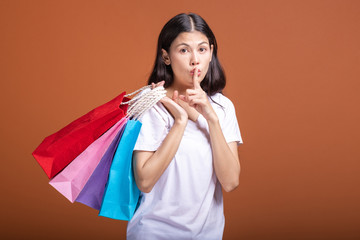 Woman holding shopping bag isolated in orange background.