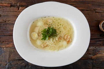 Chicken soup with noodles and vegetables in white bowl