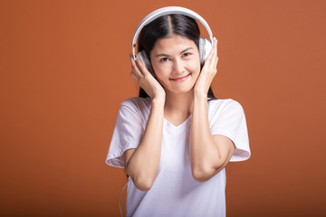 Wall Mural - Woman using headphone isolated over orange background.