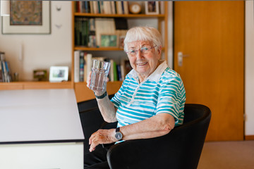 Wall Mural - Elderly woman drinking water at home