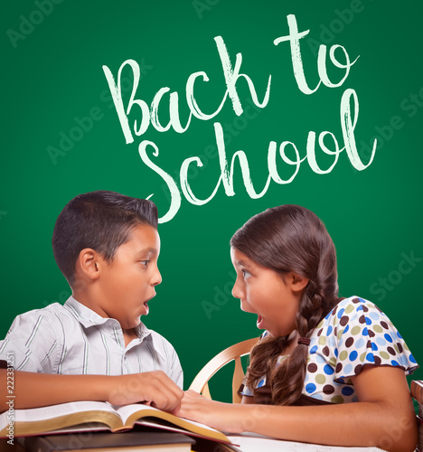 Back To School Written On Chalk Board Behind Hispanic Boy and Girl Having Fun...