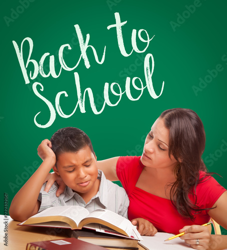 Back To School Written On Chalk Board Behind Hispanic Young Boy and Famale Ad...