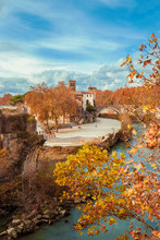 Autumn And Foliage In Rome. Red And Yellow Leaves Near Tiber Island With Two Ancient Bridges And Beautiful Sky, In The City Historic Center