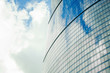 Fragment of a wall of a skyscraper with mirror glass against a sky with clouds. Close-up.