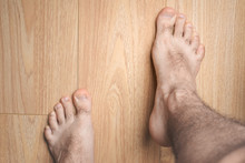 Male Feet Stand On Wooden Floor