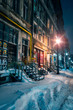 Beautiful old alley covered with snow in the winter with old buildings shot in the night well illuminated by street lamps