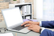 © New Africa - Man using laptop at table in office