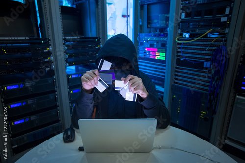 Fotografía Hacker holding credit card and using computer laptop for credit card hacking