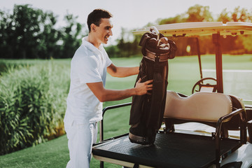 Young Man in White Shirt using Cart on Golf Field.