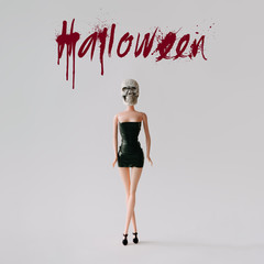 Girl doll with Halloween skull costume. Minimal holiday concept.