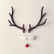 Santas reindeer made of antlers, white sunglasses and red New Year bauble decoration. Minimal winter holiday concept.