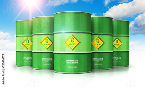 Group of green biofuel drums against blue sky with clouds and sun light