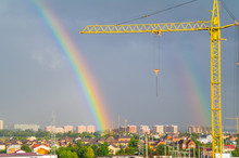 Construction Cranes Against The Sky With A Rainbow