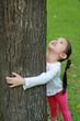 © zilvergolf - Close-up child girl hugging a tree with looking up at the park.